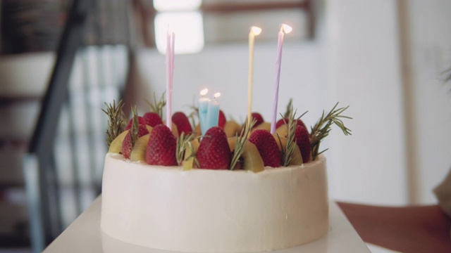 女人拿着插着生日蜡烛的蛋糕。视频下载