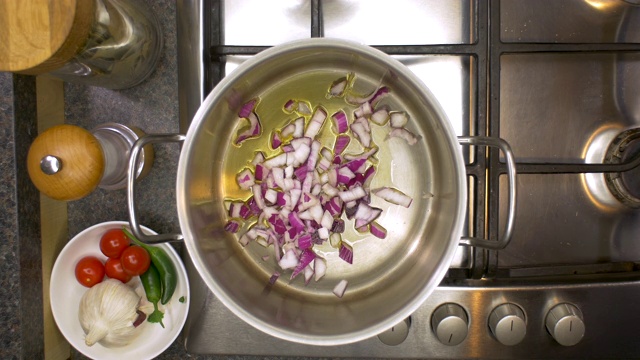 厨房铁架与洋葱，芹菜和胡萝卜被添加到炖锅的俯视视图。视频素材