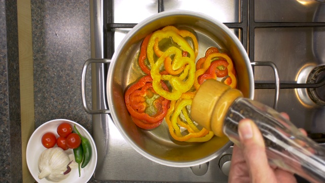厨房炉灶与辣椒被加热在平底锅和黑胡椒添加。视频素材