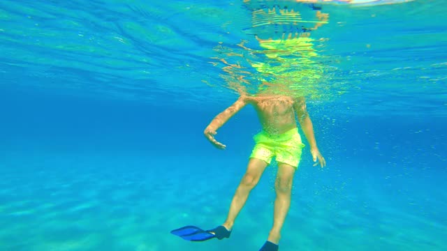 男孩戴着潜水面罩，脚蹼在水下摆动视频素材