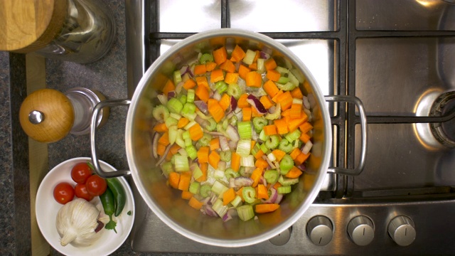 厨房铁架上的洋葱，芹菜和胡萝卜在平底锅里煮视频下载