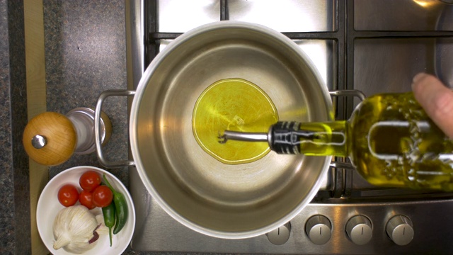 在平底锅中加热橄榄油的厨房铁架的俯视视图。视频素材