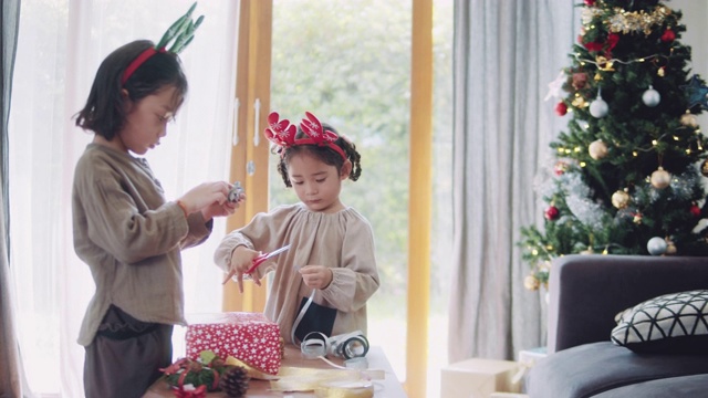 亚洲男孩和女孩协助包装圣诞礼物。视频下载