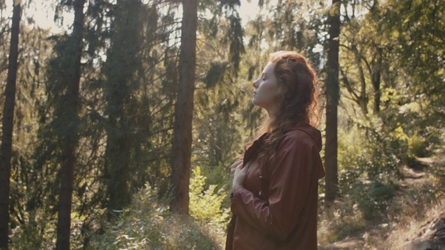 一个长红头发的女人站在森林里视频素材
