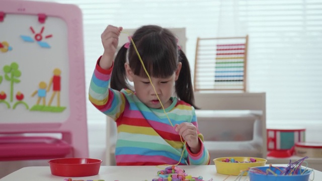 年轻的女孩把珠子穿在绳子上视频下载