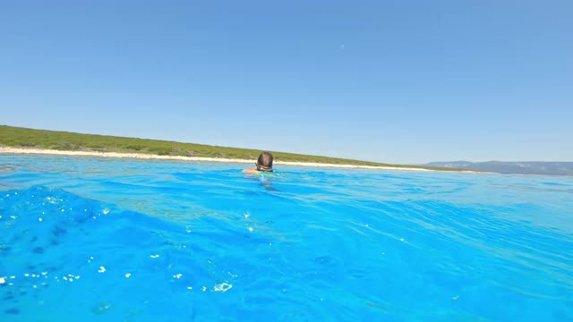 小男孩戴着潜水面罩在阳光下游泳视频素材