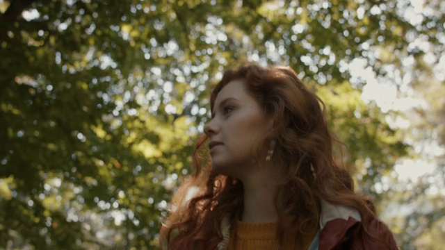 一个长着红头发的女人走在森林里视频素材