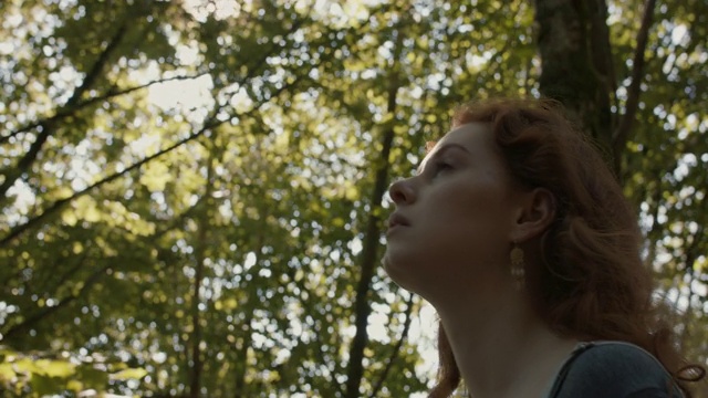 一个长着红头发的女人走在森林里视频素材