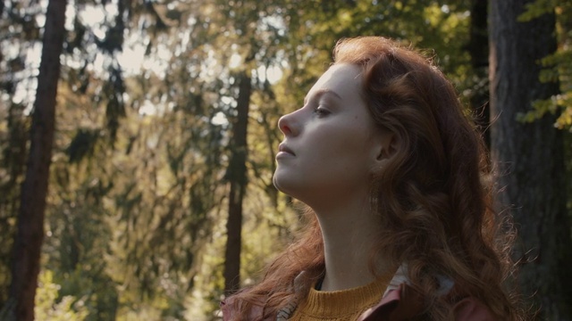 在森林里享受阳光的长红头发的女人视频下载