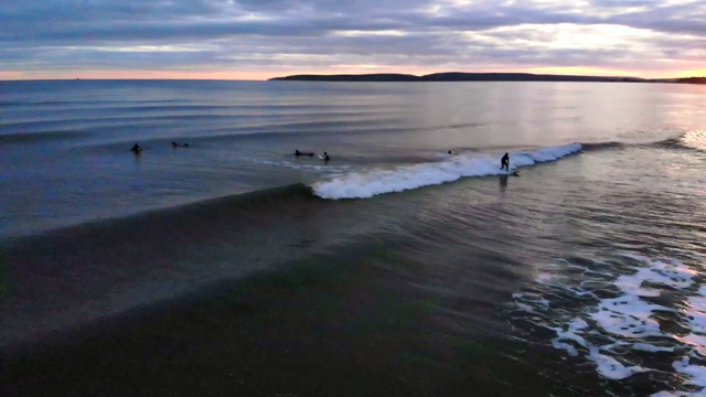 日落时分，一名冲浪者在英格兰东南海岸乘风破浪。穿着全身潜水服在冷水中冲浪视频素材