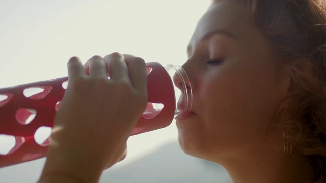 用可重复使用的玻璃瓶喝水的女人视频素材