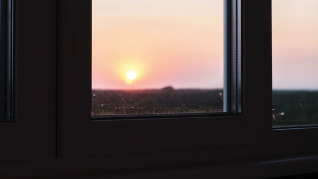 透过窗户看日落。明亮的黄色太阳越过地平线。时间流逝视频素材