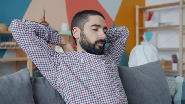 中东帅哥躺在沙发上舒展脖子的慢镜头视频素材