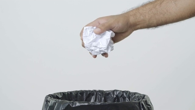 把皱巴巴的纸倒进垃圾桶。垃圾桶里满是废纸。垃圾，废纸在垃圾中孤立在白色背景上。全球气候变暖的概念。视频下载