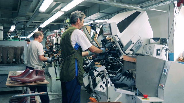男工人正在用机器制作鞋子。鞋类生产设备。视频下载