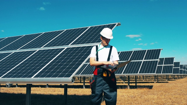 一名男性工人正在观察一个太阳能发电厂。现代太阳能电池板，生态友好型能源生产。视频下载