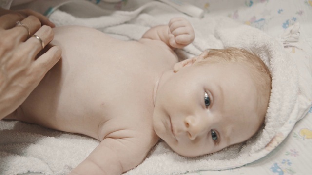 一个小婴儿躺在床上，他的妈妈用胶带包扎他的肚脐视频素材