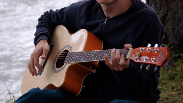 在河边放松和弹吉他的男人视频下载