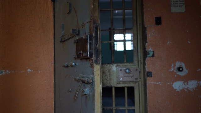 监狱金属门保护囚犯从里面逃跑。通过监狱牢房的食物通道。监狱，监禁细节，犯罪，司法。监狱内部。视频素材
