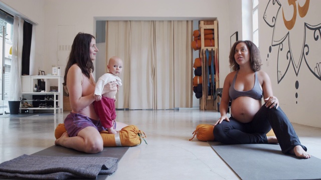 两个朋友在瑜伽课后聊天的慢动作视频，其中一个怀孕了，另一个有小孩视频下载