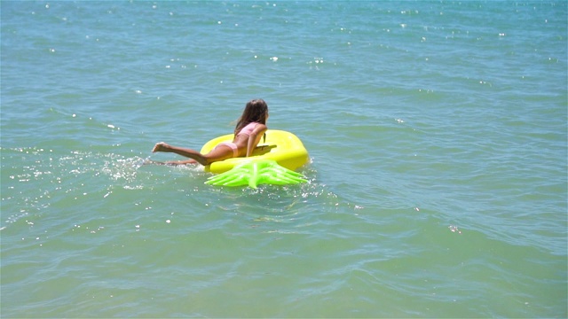 可爱的女孩在海上的充气床垫上视频下载