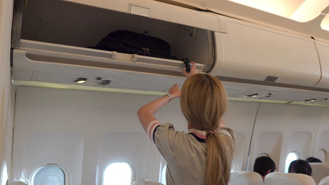 女孩把她的背包放在头顶的行李柜里视频下载