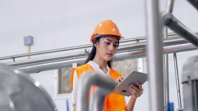 亚洲女工程师戴安全帽，用触屏平板电脑对重工业的工作过程进行安全操作。女性在干视频下载