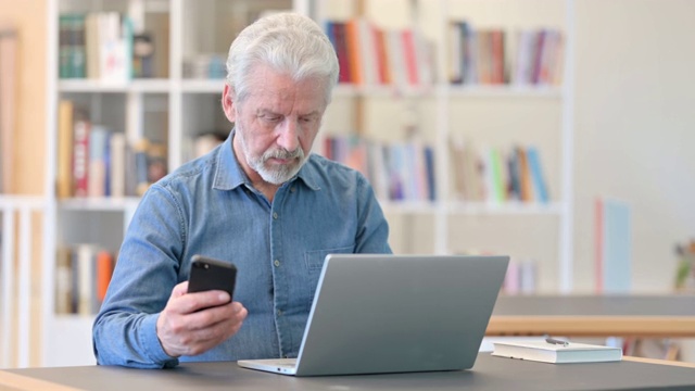 专业老人在图书馆使用智能手机和笔记本电脑视频素材