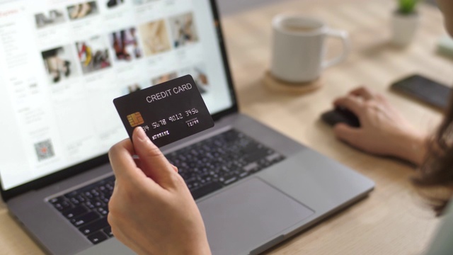 女人手里拿着信用卡，正在网上购物，用笔记本电脑在网上商店购物视频素材