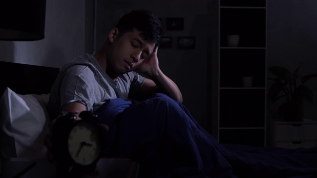 年轻的亚洲男子失眠躺在床上。视频素材