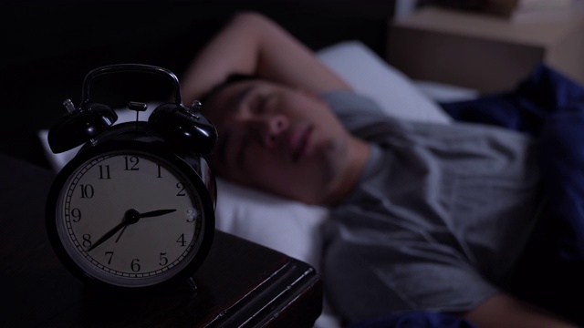 年轻的亚洲男子失眠躺在床上。视频素材