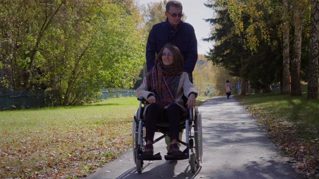 一个坐轮椅的女人和男朋友在秋天公园视频下载