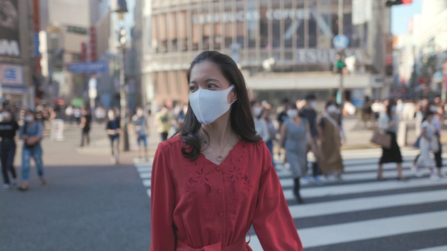 年轻女子身穿红色衣服，戴着防护面罩，走在涉谷十字视频下载