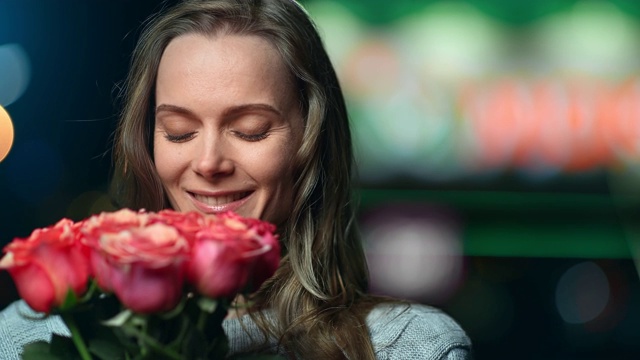 快乐的女性摆姿势与玫瑰花享受晚上的约会。中近距离拍摄4k红色相机视频下载