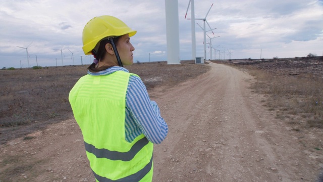 可再生能源系统。电力维护工程师在一个风电场工作，她的身后是晴朗的蓝天。视频素材