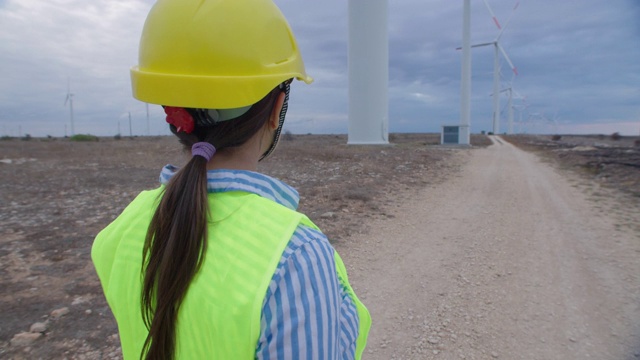 可再生能源系统。电力维护工程师在一个风电场工作，她的身后是晴朗的蓝天。视频素材