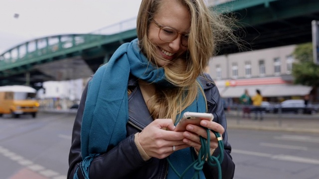 微笑的女人在城市的街道上使用智能手机视频素材