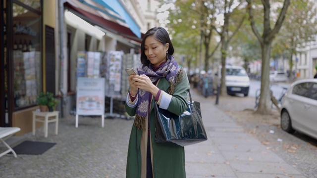 一名女子在城市人行道上查看智能手机视频素材