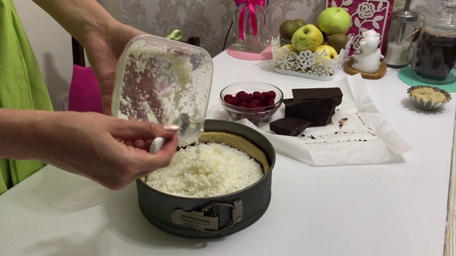 一个女人把椰子片放在巧克力甘纳许和烤饼干上。烹饪Levington派。视频素材