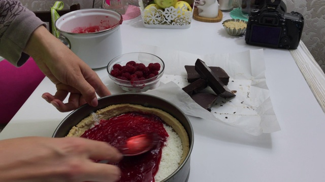 一个女人把树莓果冻倒在椰子上。放在烤好的海绵蛋糕里。烹饪Levington派视频素材