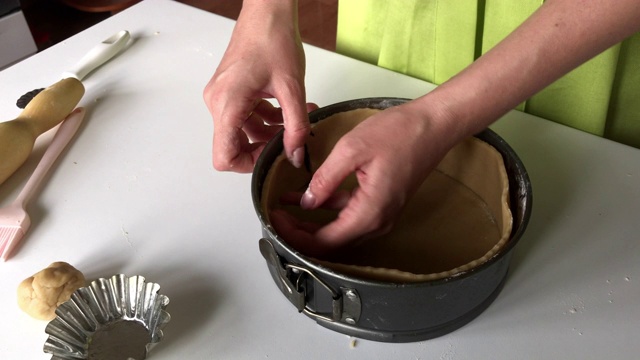 一位妇女将面团放入一个可折叠的蛋糕烤盘。烹饪Levington派。视频素材