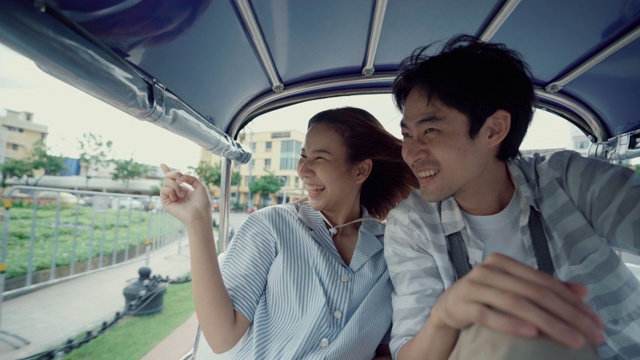 年轻英俊的男子戴着帽子和他的女朋友骑在传统的嘟嘟夫妇旅行泰国在他们的蜜月视频素材