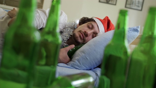 醉醺醺的商人拿着圣诞老人的帽子和一杯啤酒睡觉视频下载