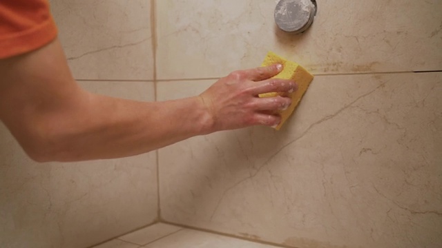用软布擦拭浴室瓷砖。一名工人用抹布擦拭浴室的瓷砖。视频素材