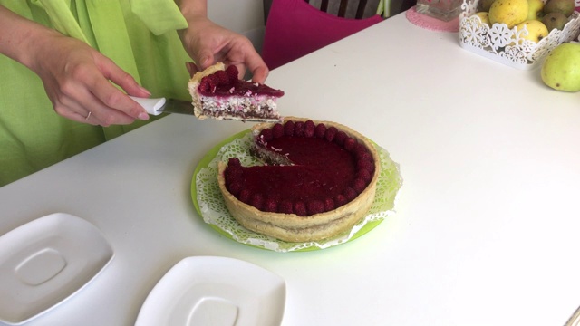 一个女人用覆盆子果冻切莱文顿蛋糕。点缀以树莓视频素材