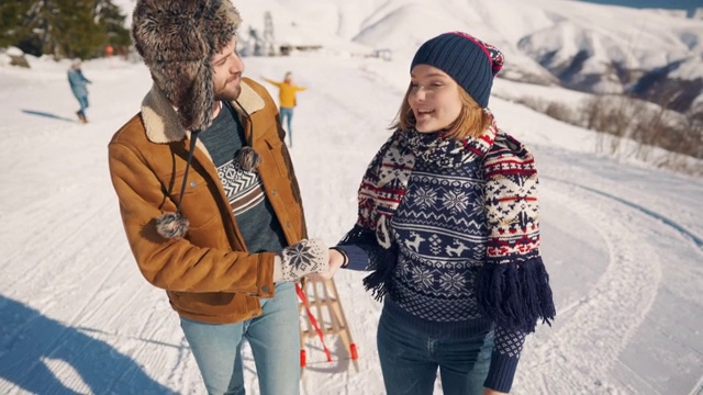 年轻夫妇一起拉着雪橇上山，享受和亲吻视频素材