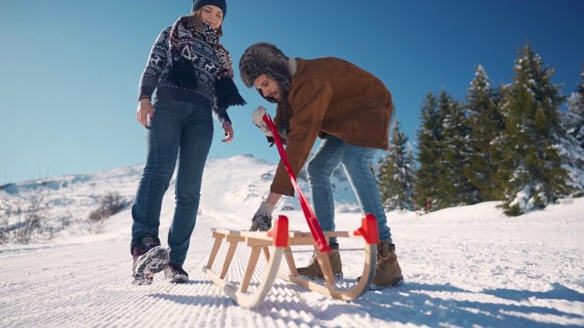 幸福的一对要乘坐新的雪橇从雪山上滑下来视频素材