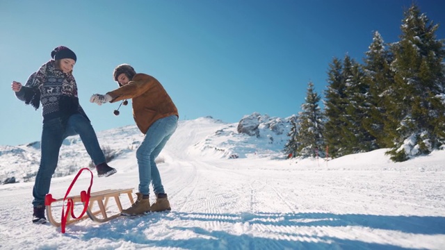 快乐的年轻夫妇从雪山上滑下来视频素材