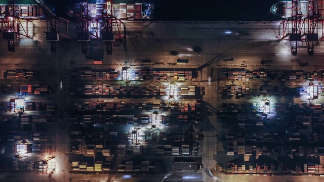 T/L PAN无人机拍摄的繁忙的工业港口，夜间有集装箱船视频素材