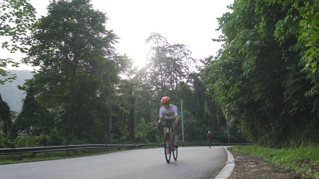 职业自行车手在乌鲁兰加乡村地区骑公路旅行与2名铁人三项运动员骑手在早上视频下载